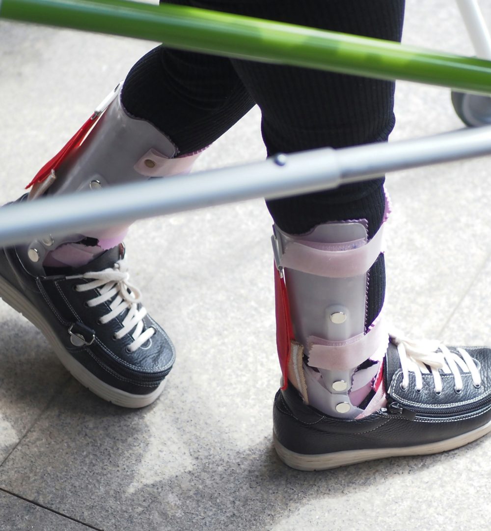 Child with ankle-foot orthoses using a walking frame