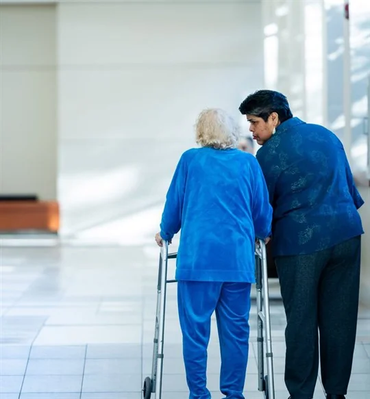 Older patient walking with support in a hospital corridor
